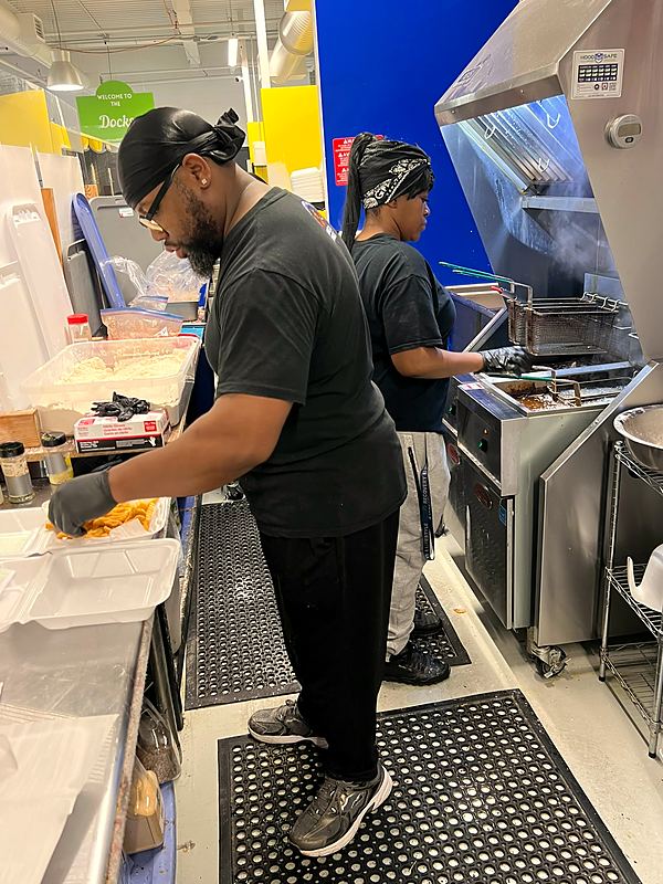 Two cooks working the line and the fryers in the kitchen