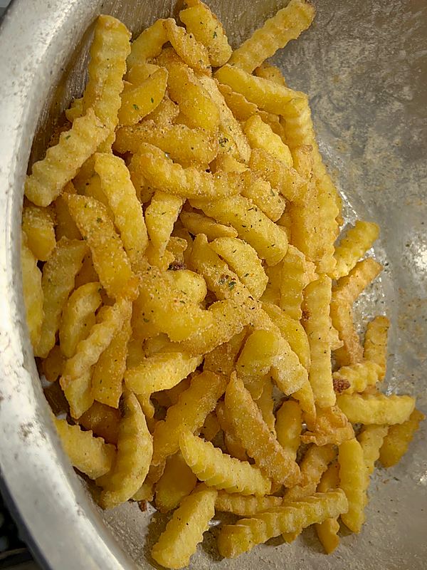 Fresh seasoned crinkle fries in a steel bowl